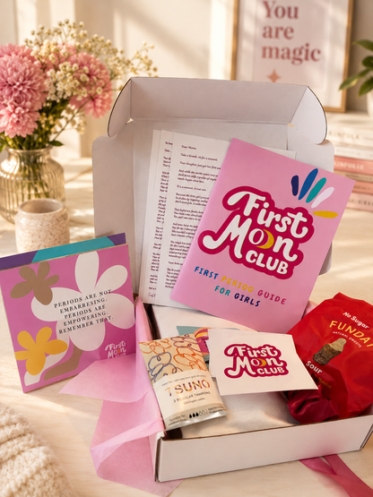 First Mom Club box with various items including a card and a t-shirt on a light surface.
