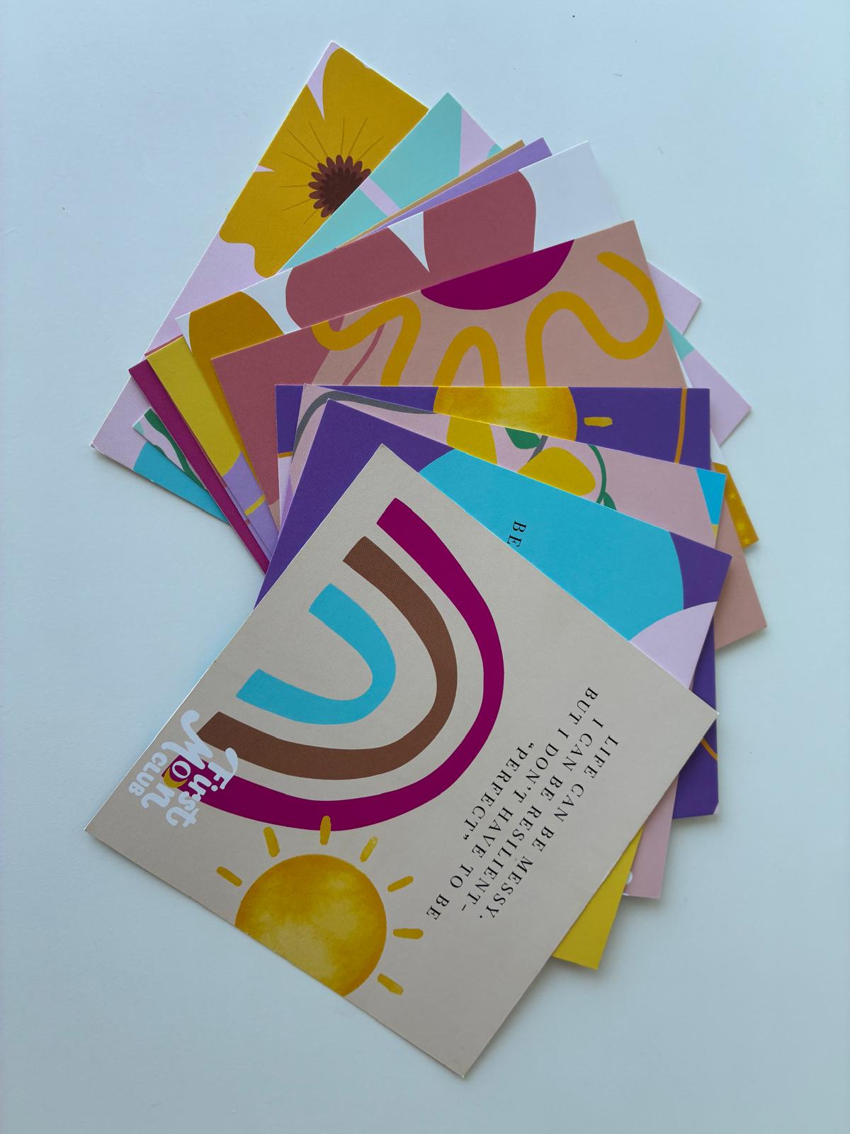 Stack of colorful greeting cards with abstract designs on a light blue background